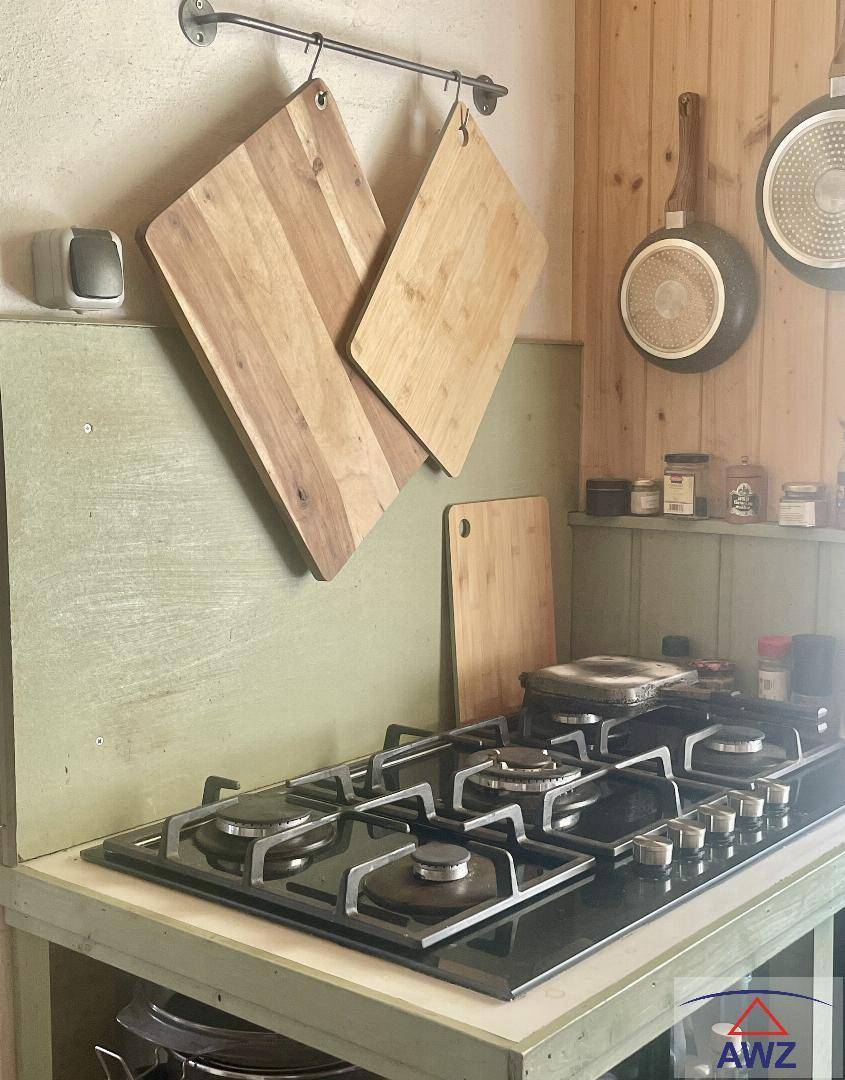 Rustikale Küche mit Gaskochfeld, hölzernen Schneidebrettern und grünen Wandpaneelen.