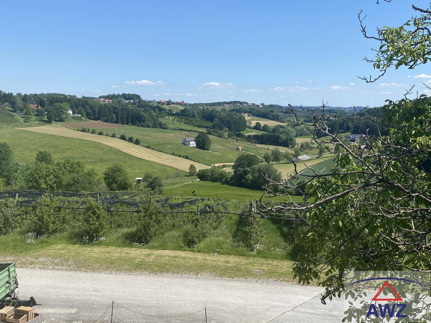 Panoramablick über eine hügelige Landschaft mit Feldern, Wäldern und verstreuten Häusern.