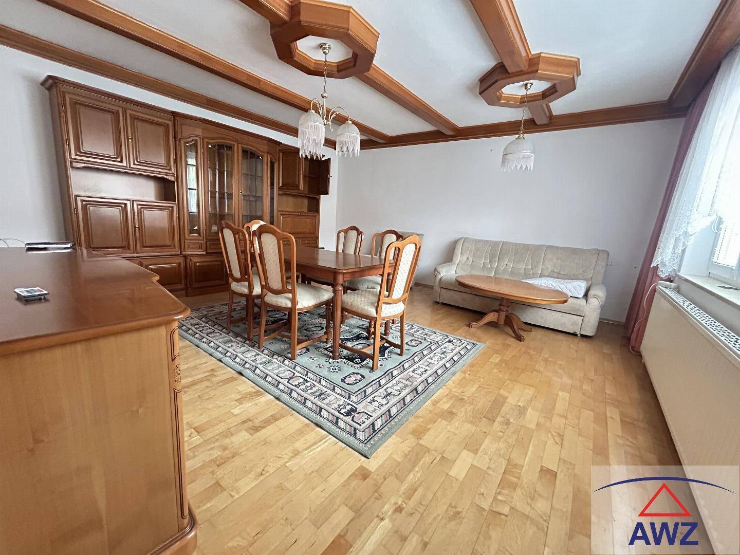 Traditioneller Wohn- und Essbereich mit Holzmöbeln, Parkettboden und dekorierter Decke.