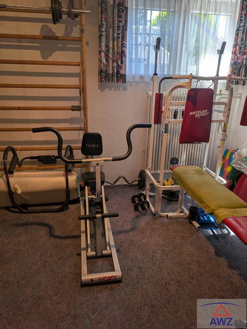 Fitnessraum mit verschiedenen Trainingsgeräten und Sprossenwand für sportliche Aktivitäten.