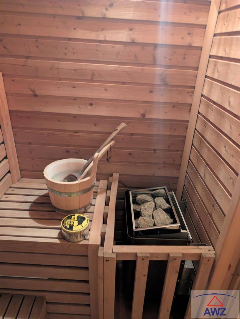 Holzvertäfelte Sauna mit traditionellem Aufgusseimer und Heizofen für entspannende Momente.