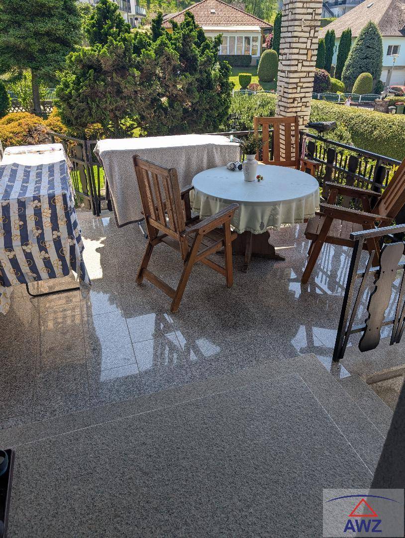 Sonnige Terrasse mit Granitfliesen und Gartenmöbeln, ideal für Mahlzeiten im Freien.