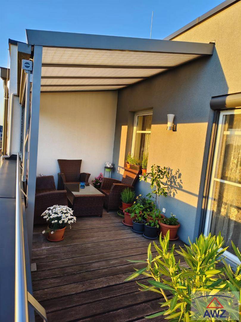 Sonniger Balkon mit Holzboden, gemütlichen Loungemöbeln und moderner Überdachung, ideal zum Entspannen.