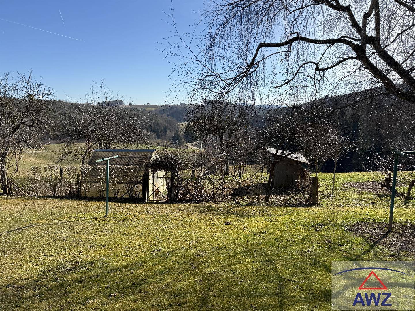 Weitläufiger Gartenbereich mit Blick auf die umliegende Hügellandschaft und alte Bäume.