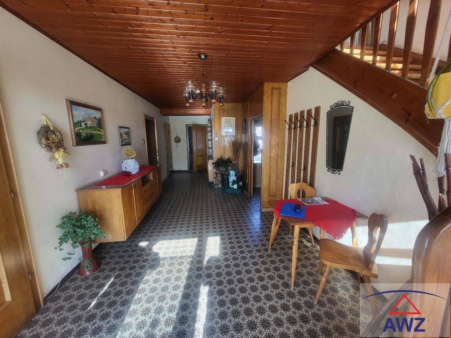 Traditioneller Flur mit gemusterten Fliesen, Holzvertäfelung und einer Holztreppe.
