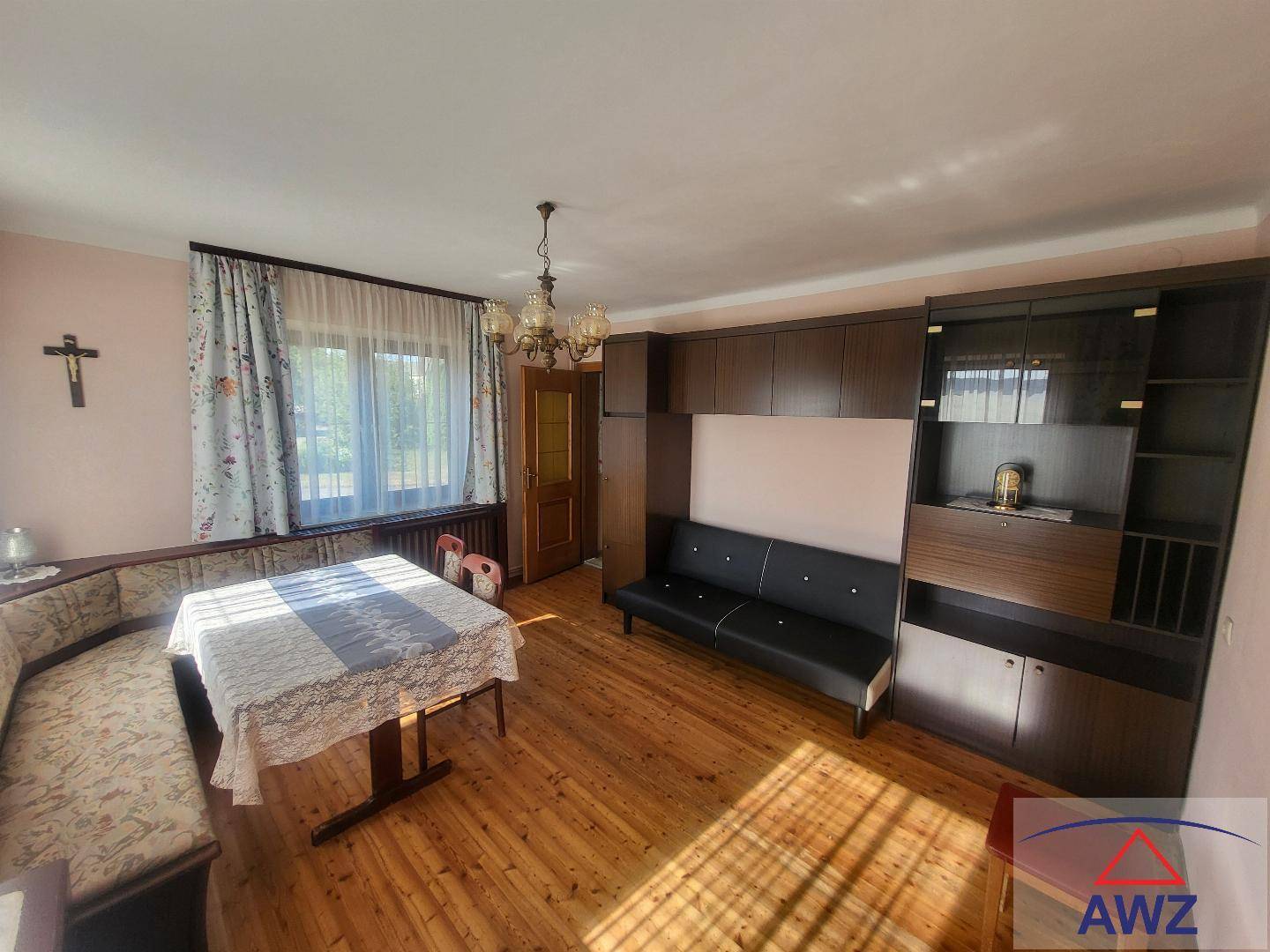 Gemütliches Wohnzimmer mit Holzboden, Eckbank, Sofa und großer Schrankwand.