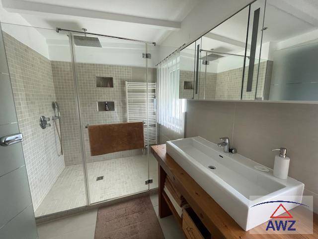 Modernes Badezimmer mit ebenerdiger Dusche, Einzelwaschbecken und beheiztem Handtuchhalter.