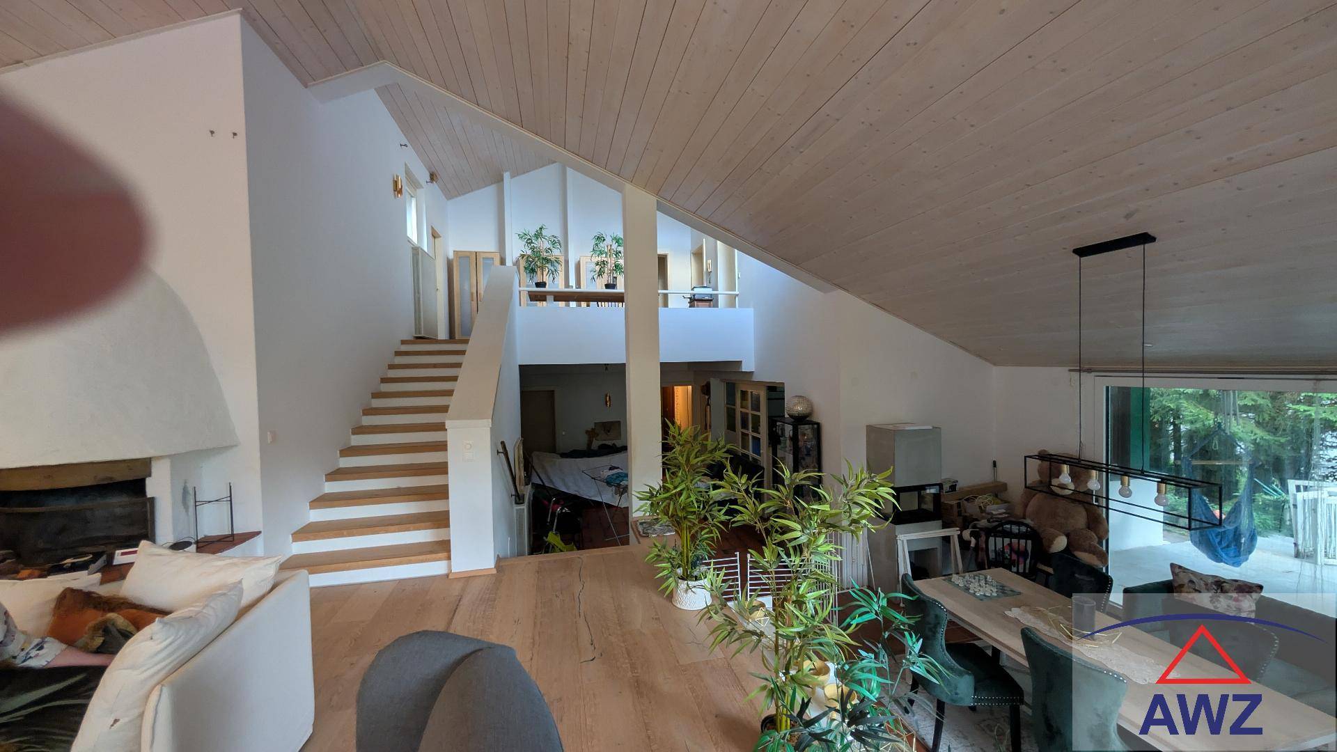 Heller, offener Wohn-Essbereich mit hohen Holzdecken, Holzboden und Kamin.