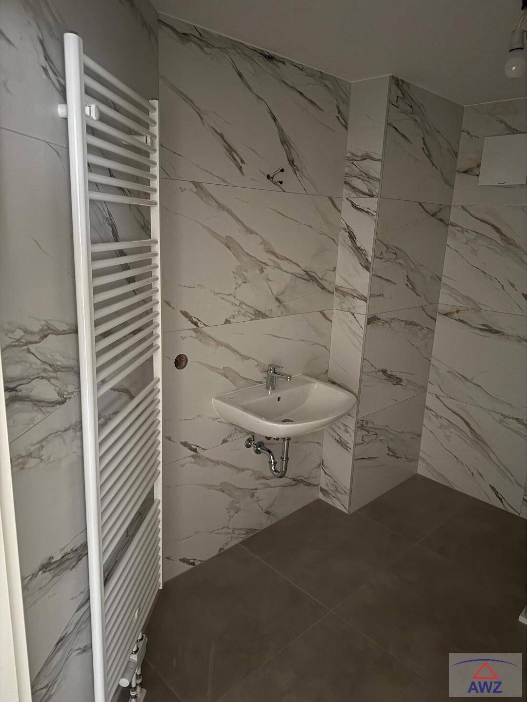 Helles Badezimmer mit modernem Waschbecken, Handtuchheizkörper und Marmoroptik-Fliesen.
