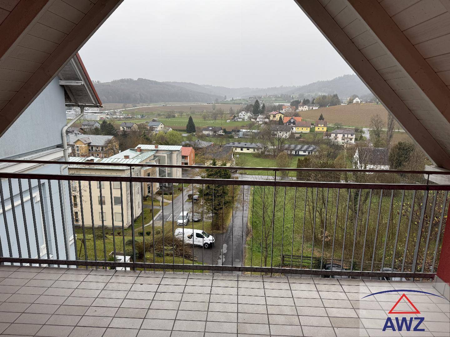 Geräumiger Balkon mit weitem Blick über die grüne Landschaft und umliegende Häuser.