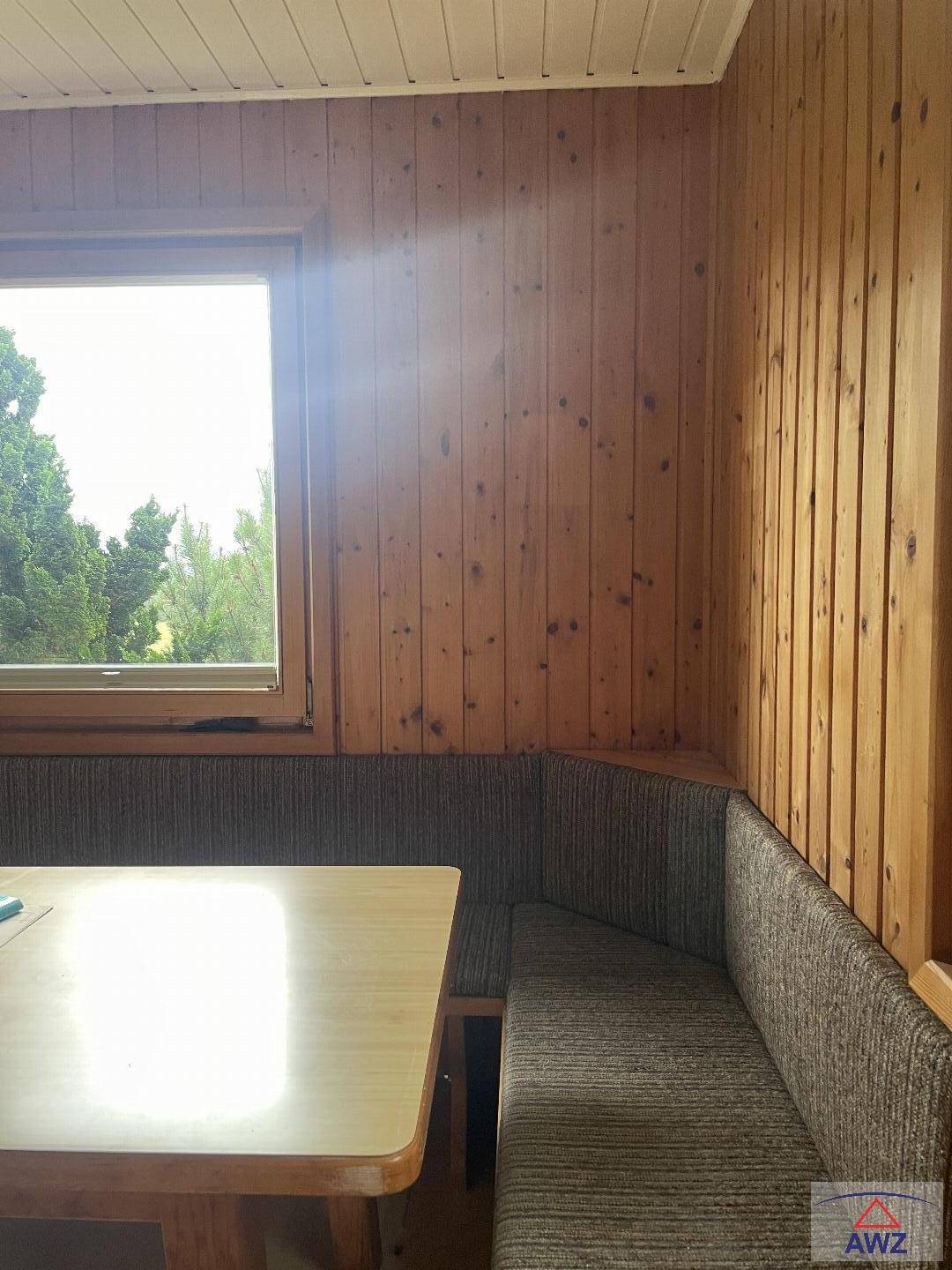 Gemütliche Essecke mit Holztäfelung, eingebauter Sitzbank und Blick ins Grüne durch das Fenster.