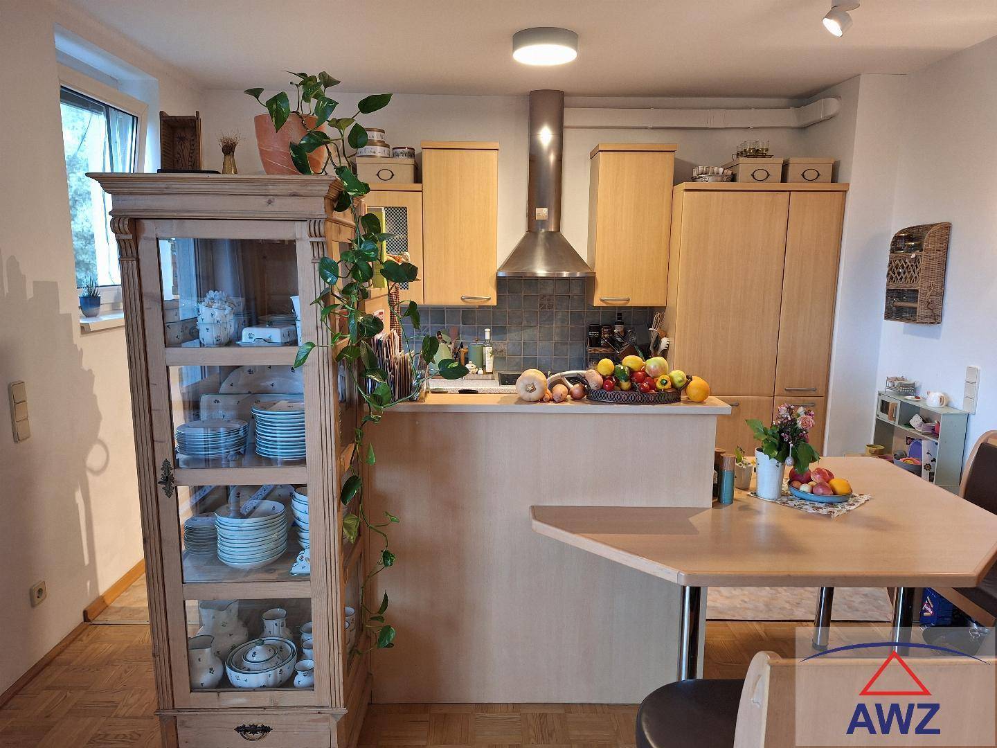 Helle Küche mit Holzschränken, integrierter Dunstabzugshaube und Essbereich.