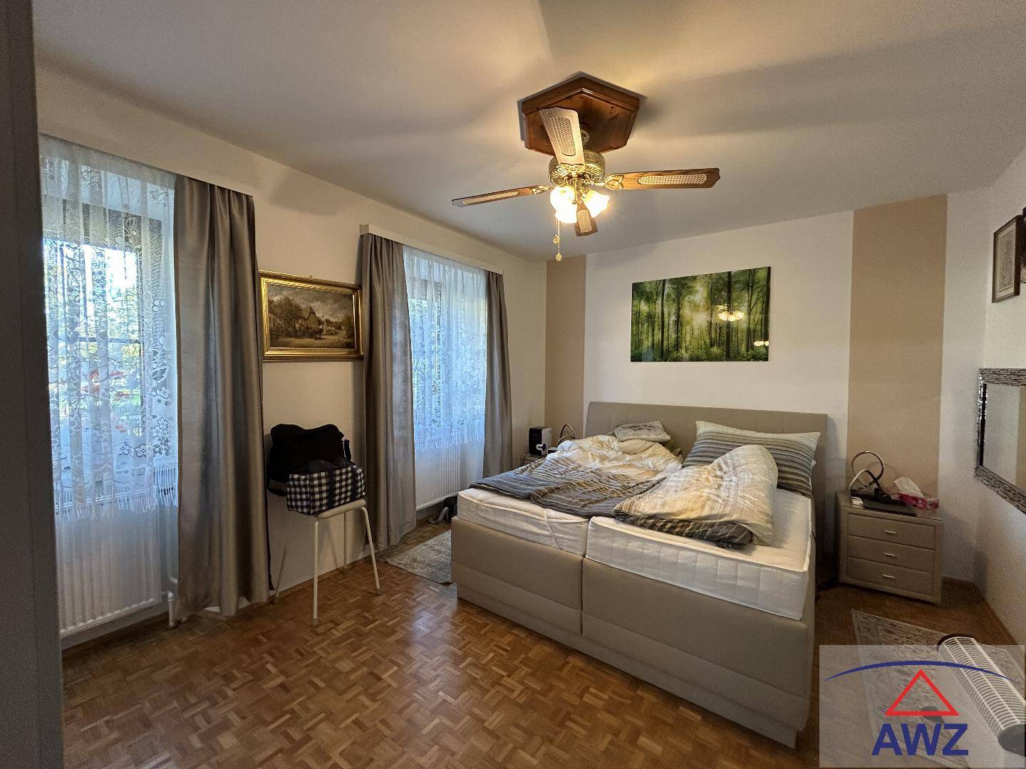 Gemütliches Schlafzimmer mit Doppelbett, Deckenventilator und Parkettboden.