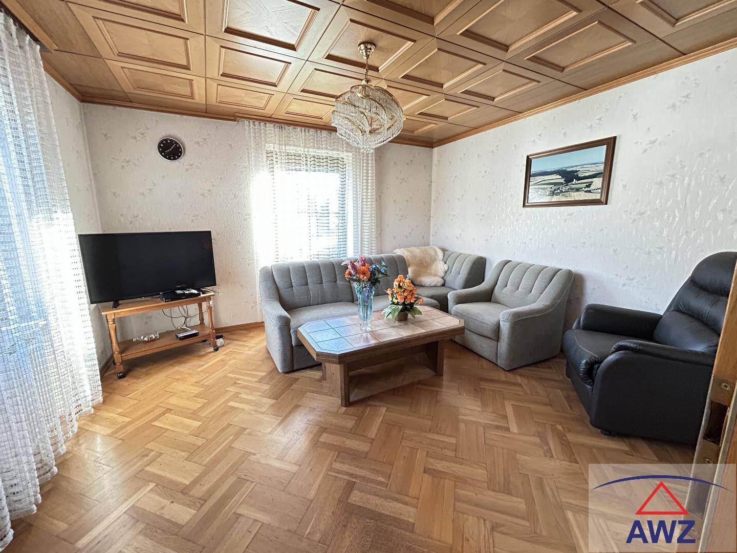 Helles Wohnzimmer mit Parkettboden, Holzdecke und traditionellen Möbeln.