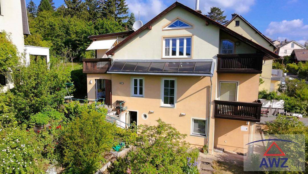 Mehrstöckiges Wohnhaus mit mehreren Balkonen und üppigem Gartenbereich.