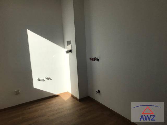 Unmöblierter Raum mit sichtbaren Wasseranschlüssen und hellem Lichteinfall durch ein Fenster.
