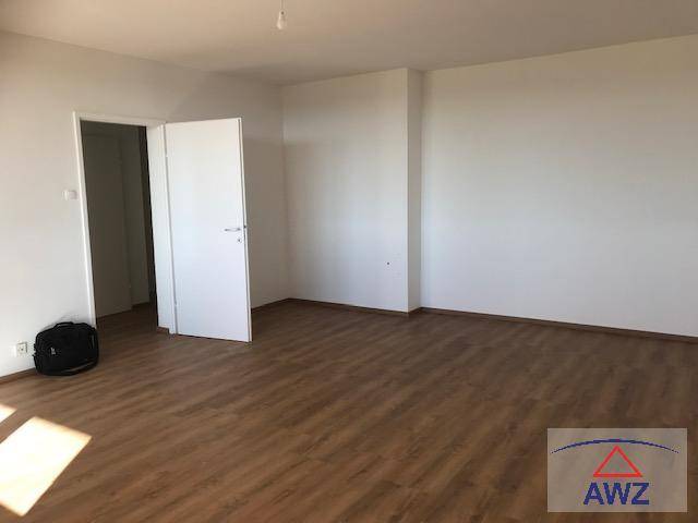 Geräumiger, unmöblierter Raum mit Laminatboden und einer Tür, die zu einem weiteren Zimmer führt.