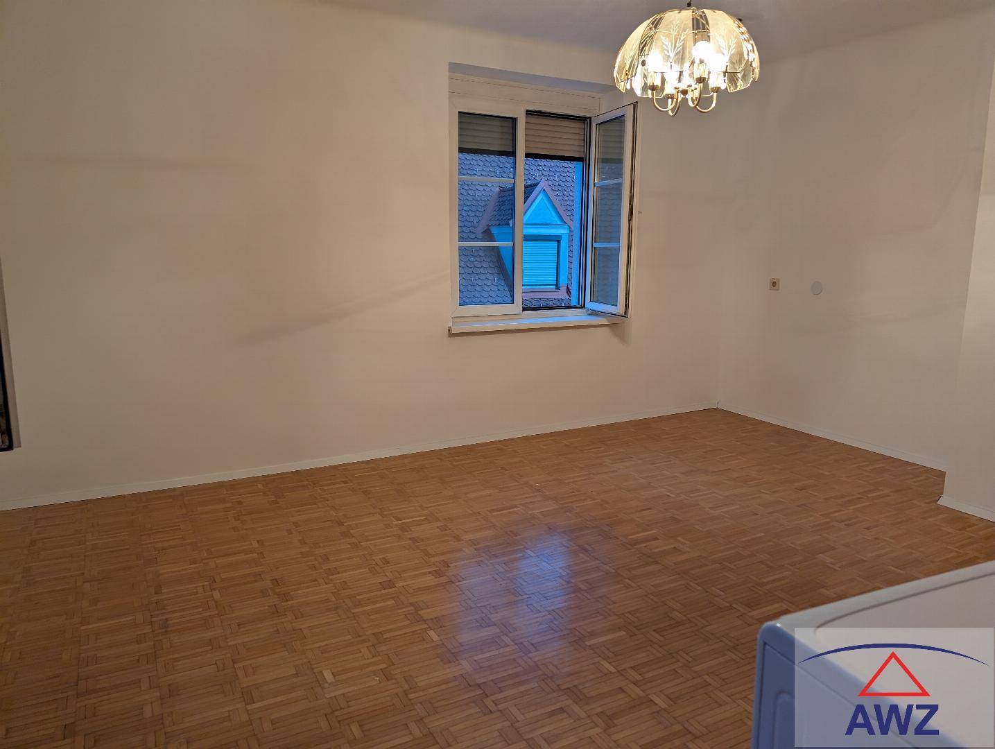 Heller, leerer Raum mit Parkettboden und einem Fenster, bereit zur individuellen Gestaltung.