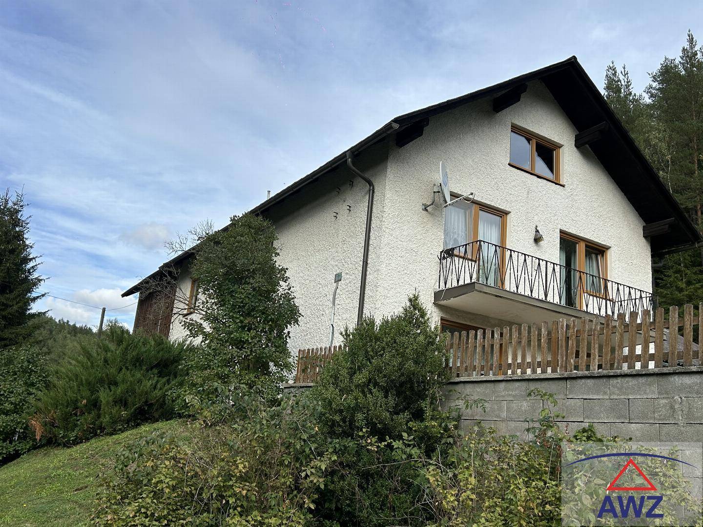 Traditionelles Haus mit Balkon und Blick auf die bewaldete Umgebung.