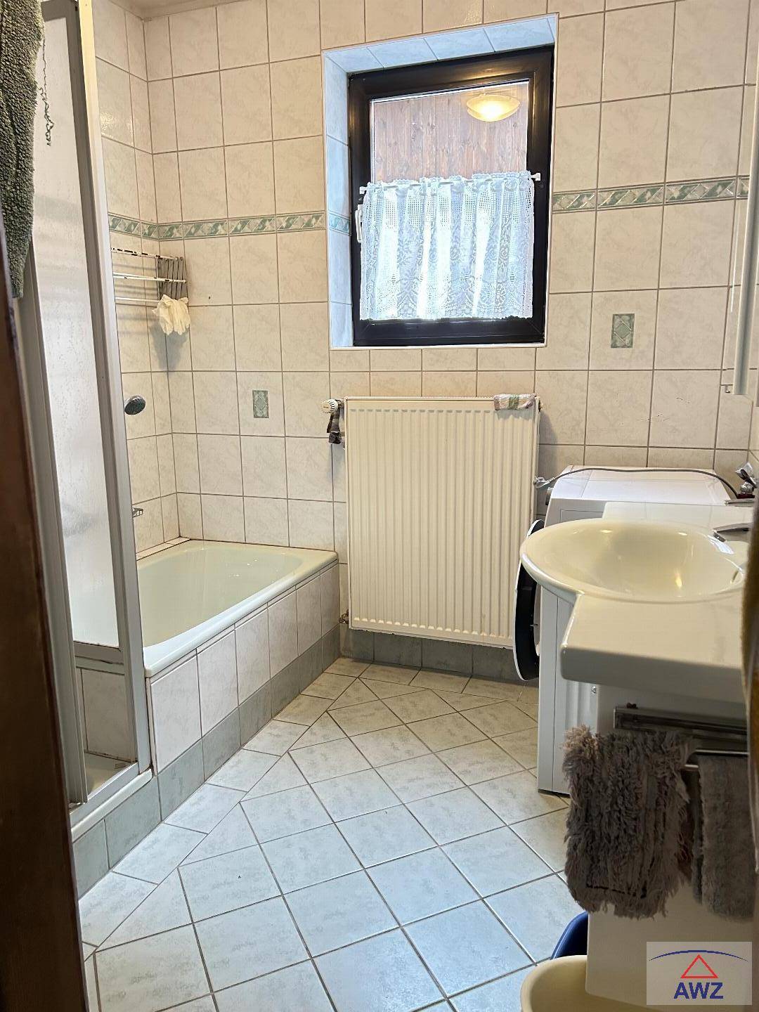 Helles Badezimmer mit Badewanne, Dusche, Fliesenboden und Fenster.