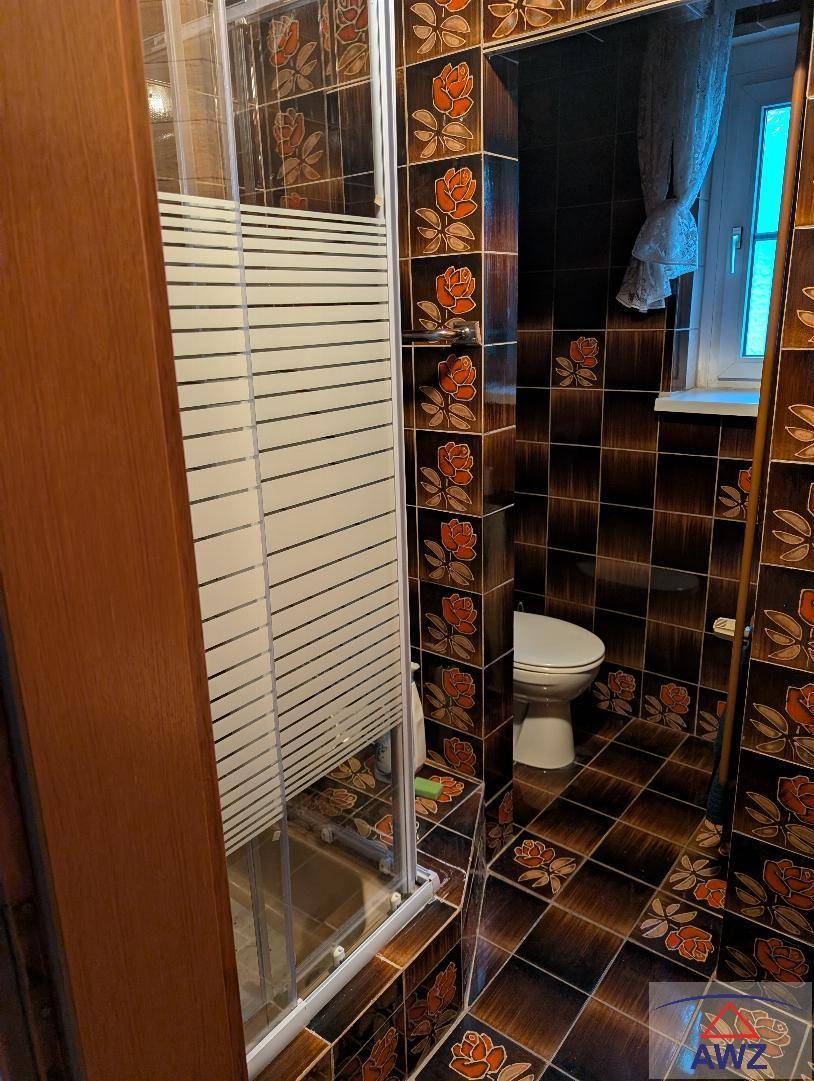 Badezimmer mit auffälligen braunen Fliesen, floralem Muster und einer Duschkabine.