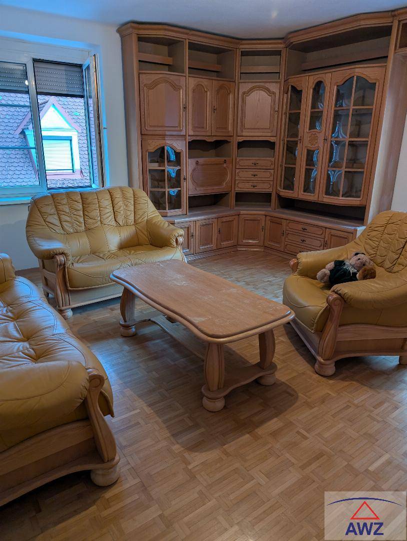 Gemütliches Wohnzimmer mit traditionellen Holzmöbeln, Ledersofas und Parkettboden.