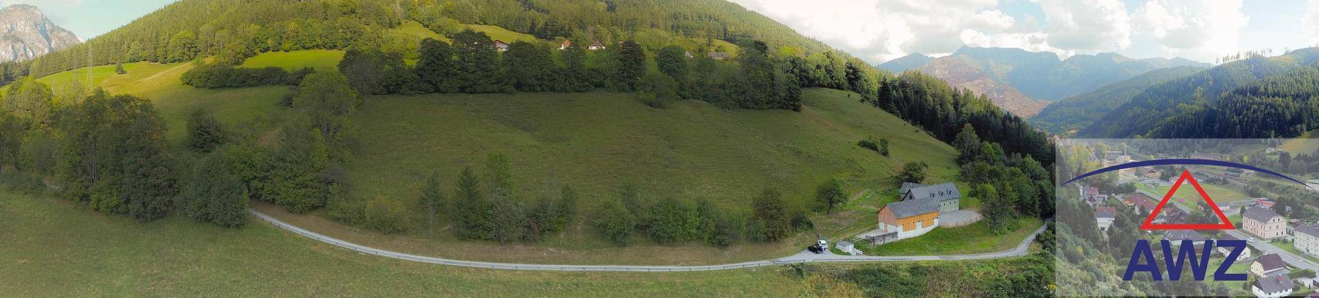 Panoramische Luftaufnahme eines Anwesens in einer weiten, grünen Berglandschaft mit Fernblick.