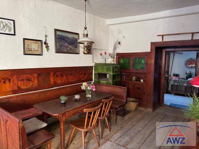Gemütlicher Essbereich mit Holzbänken, Holztisch und einem traditionellen grünen Kachelofen.
