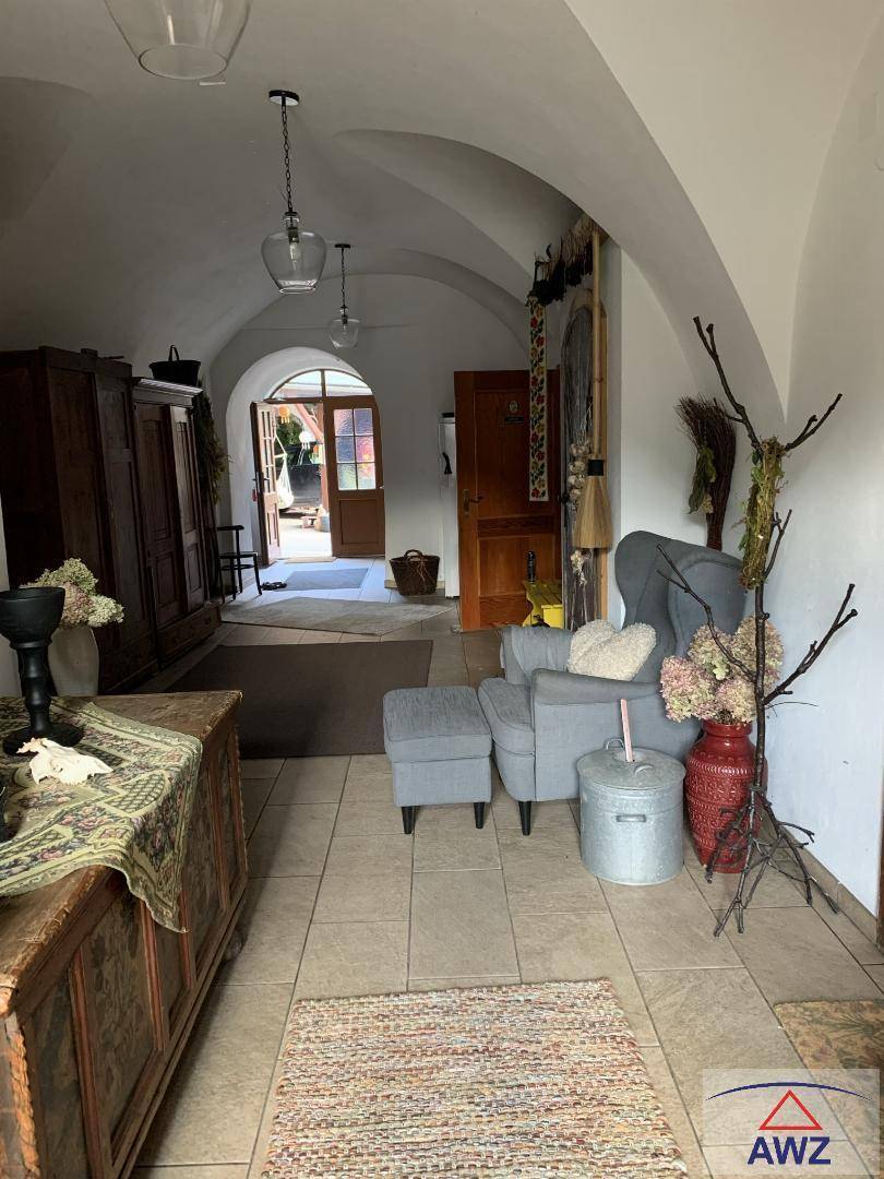 Heller Eingangsbereich mit Gewölbedecke, Fliesenboden und rustikalen Möbeln, führt nach draußen.