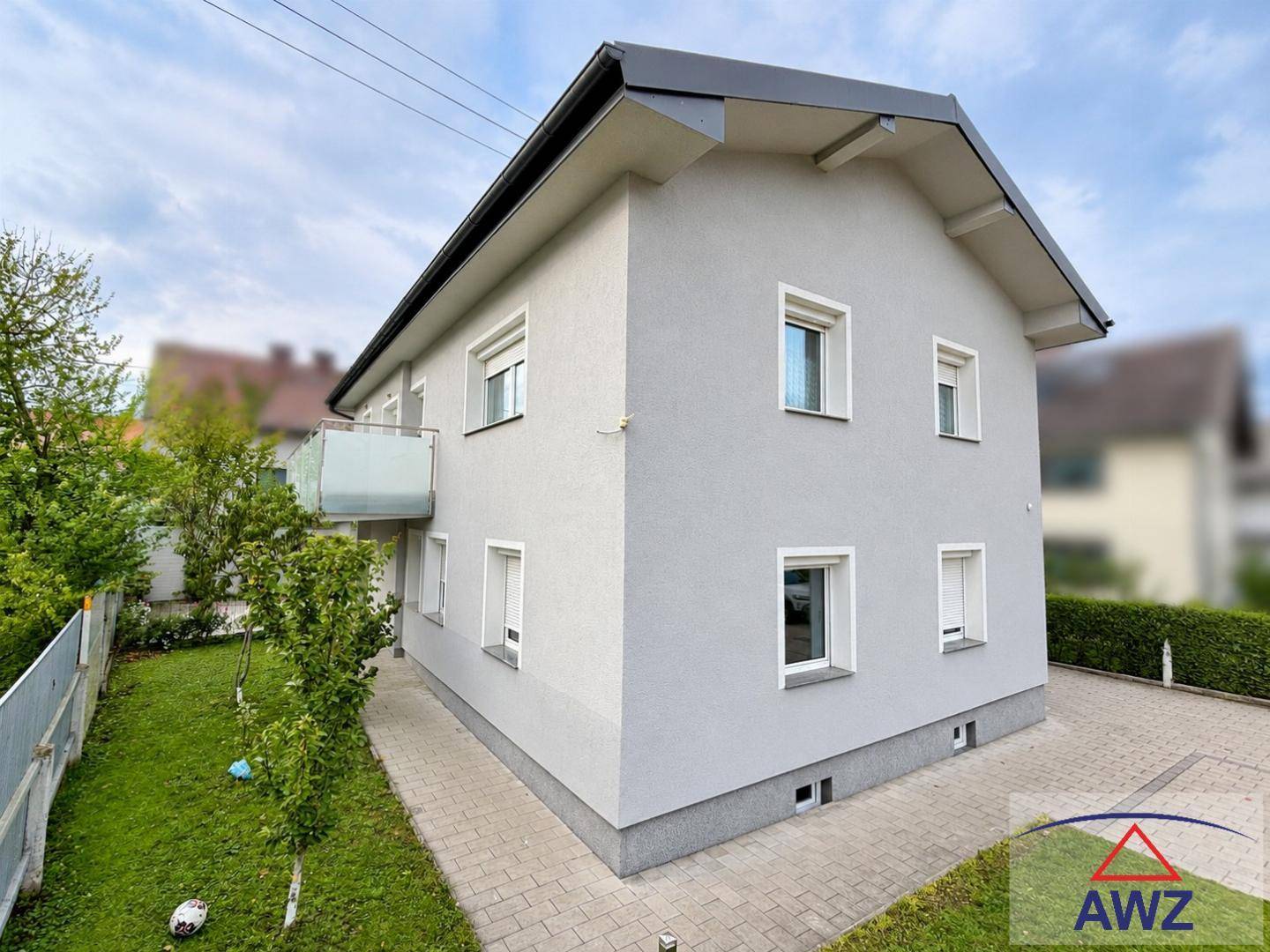 Modernes Einfamilienhaus mit heller Putzfassade, Satteldach und einem gepflegten Rasenbereich im Vorgarten.