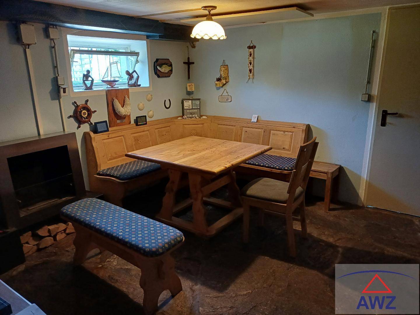 Rustikaler Kellerraum mit Holzbänken, Esstisch und kleiner Fensteröffnung für Tageslicht.