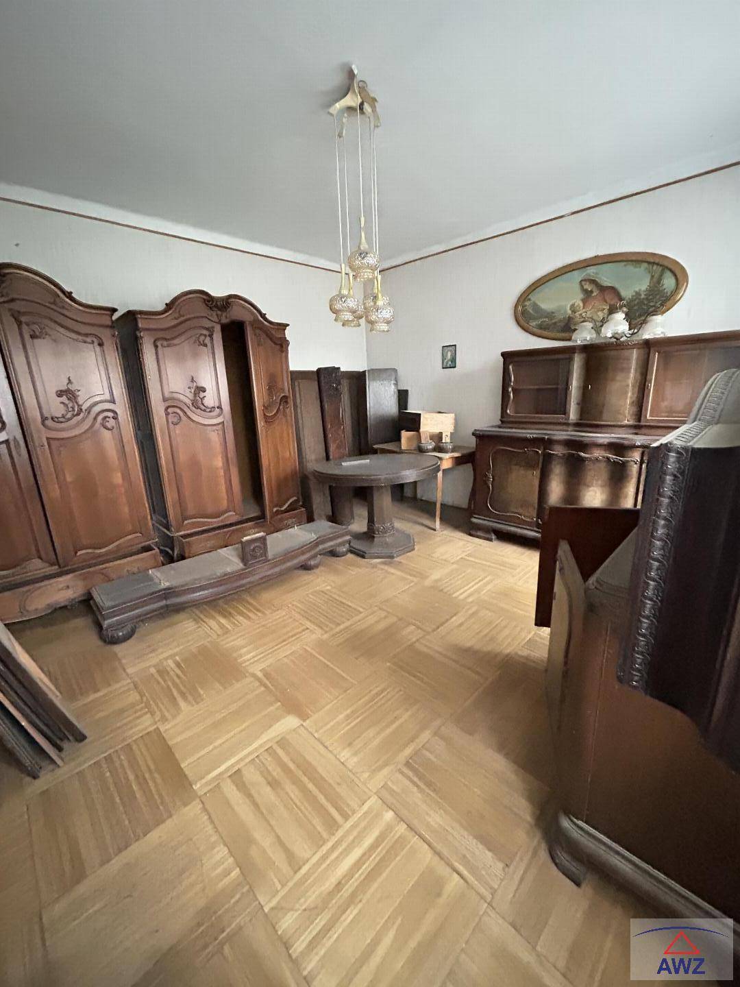 Geräumiger Raum mit Fischgrätparkett und einer Sammlung antiker Holzmöbel im Vintage-Stil.