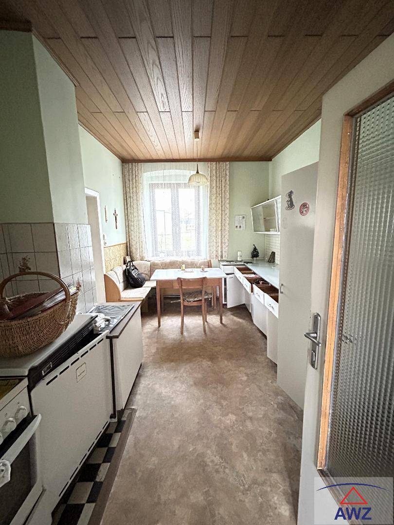 Traditionelle Wohnküche mit Holzdecke, Einbauküche und einem gemütlichen Essbereich am Fenster.