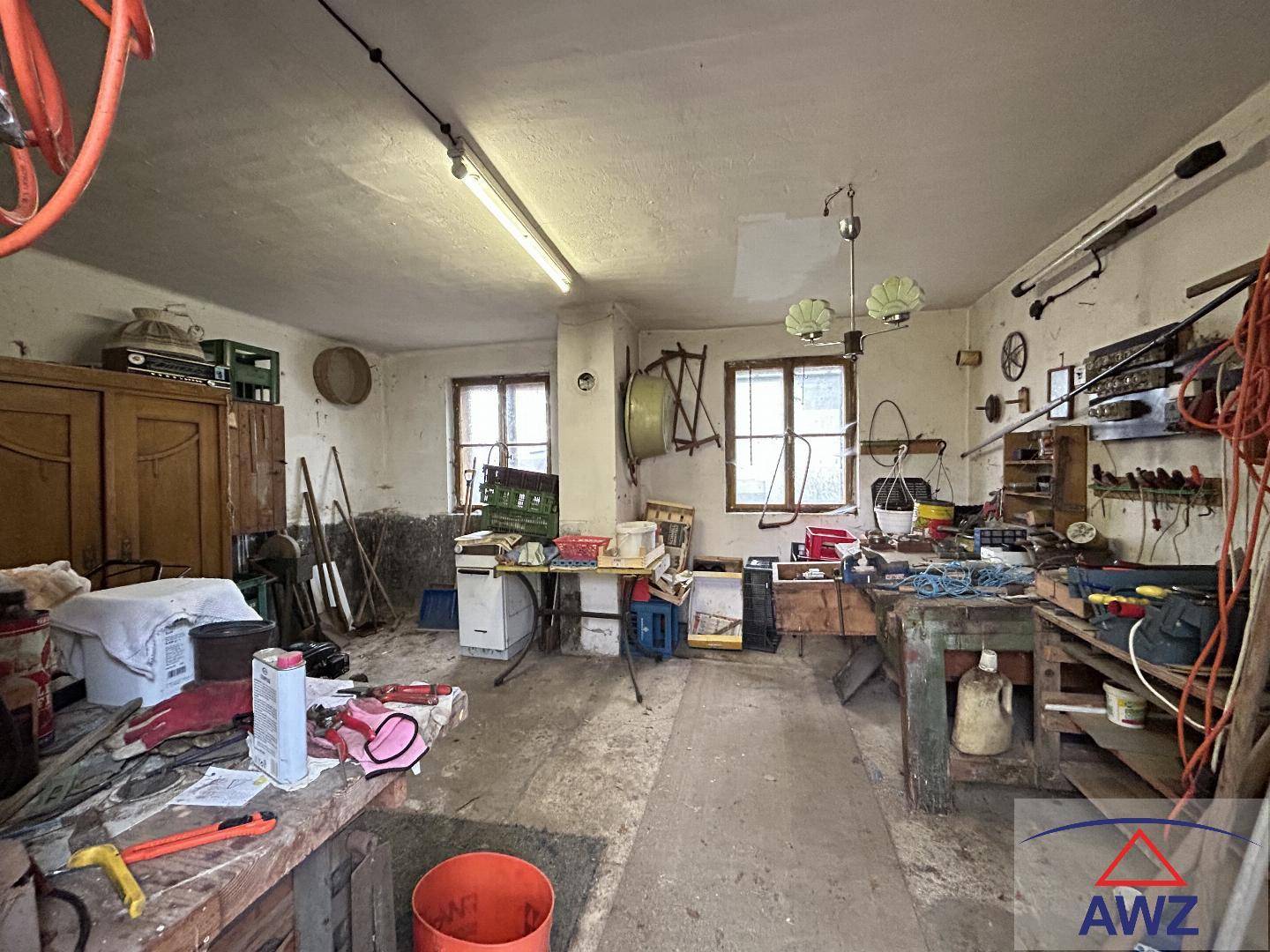 Geräumiger Werkstattraum mit zwei Fenstern, Werkbänken und einer Vielzahl von Werkzeugen und Materialien.