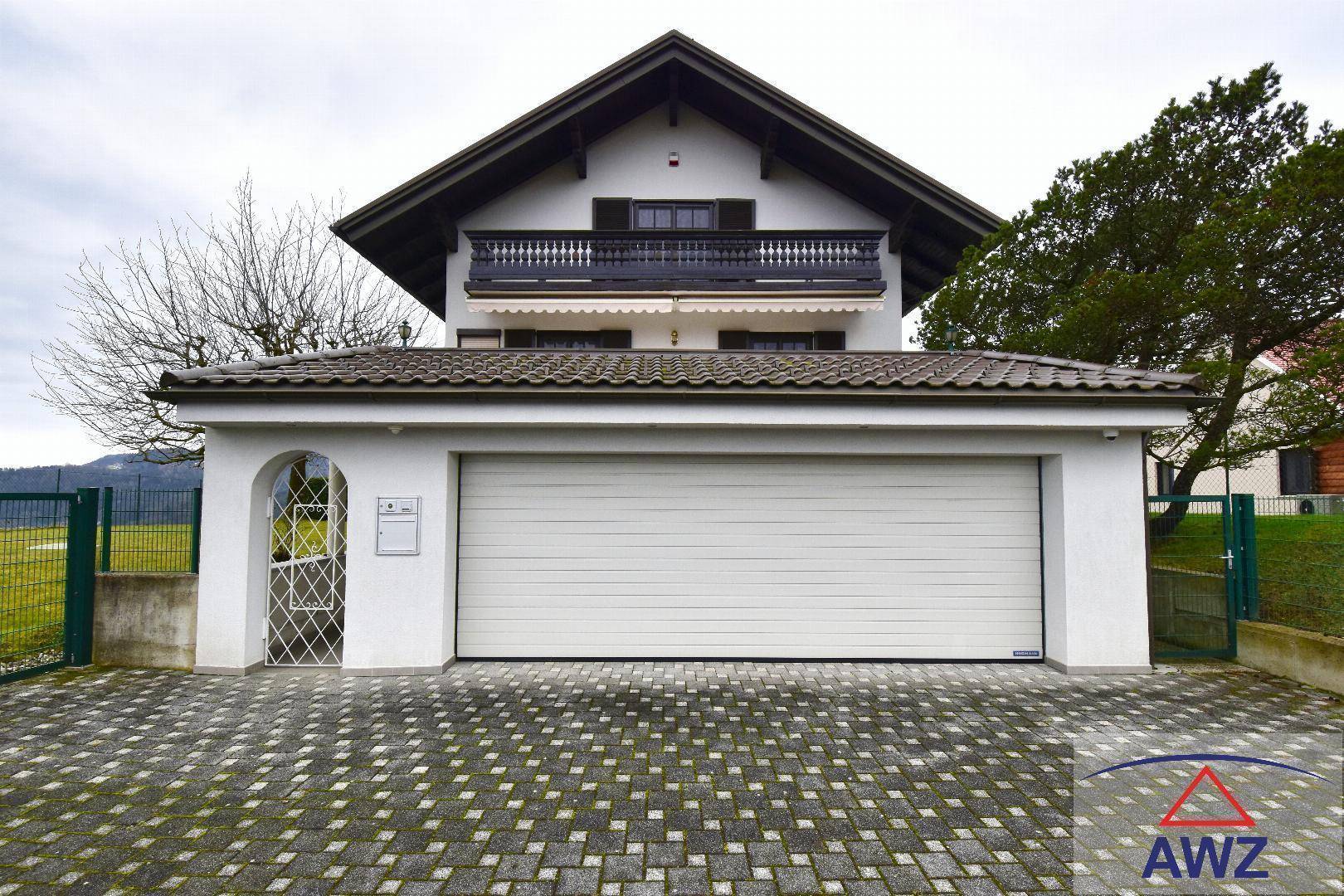 Vorderansicht des Hauses mit großer Doppelgarage und gepflasterter Einfahrt.