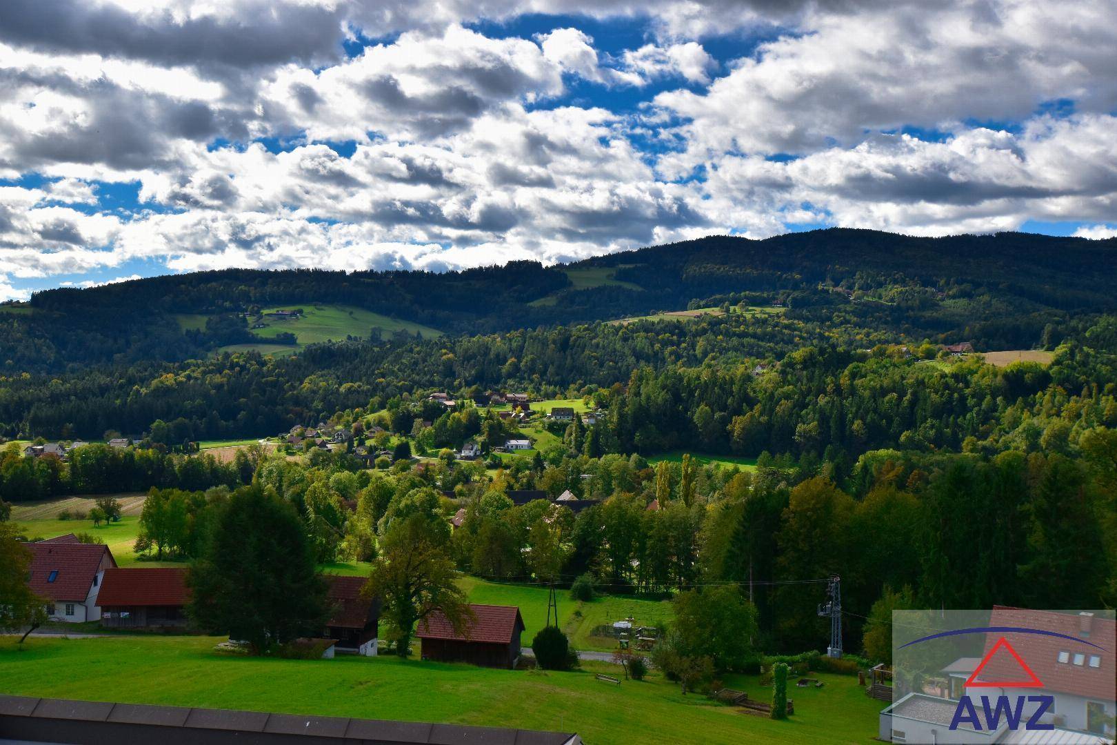 Panoramablick auf die malerische Hügellandschaft mit Wäldern und kleinen Siedlungen.