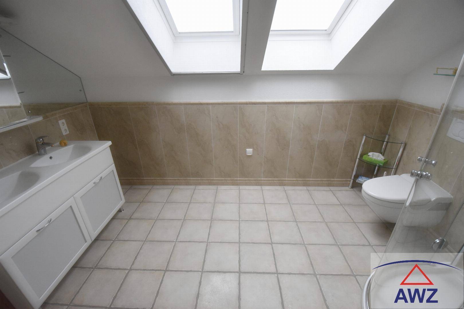 Helles Badezimmer im Dachgeschoss mit beigefarbenen Fliesen, Doppelwaschbecken und Dachfenstern.