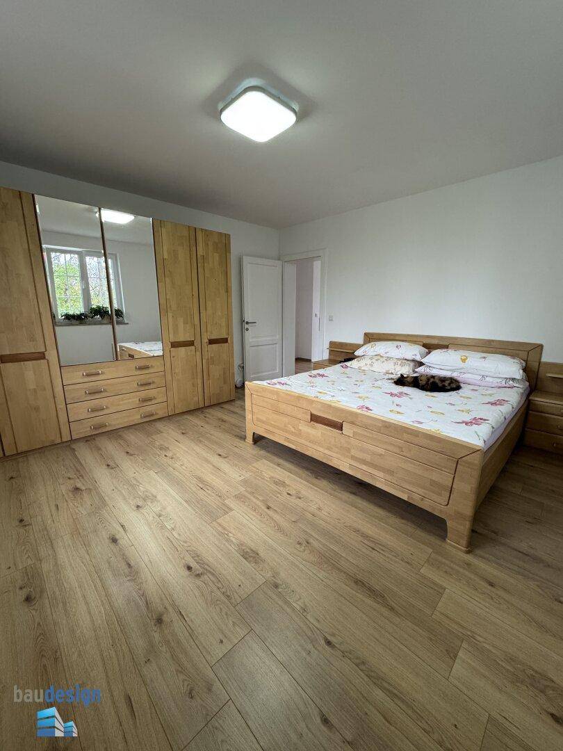 Schlafzimmer mit Holzboden, Doppelbett und großem Kleiderschrank mit Spiegelfronten.