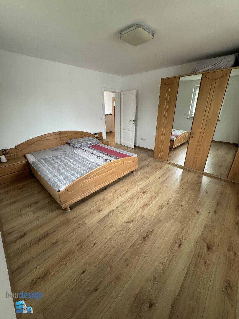 Schlafzimmer mit Holzboden, Doppelbett und großem Spiegelschrank für viel Stauraum.