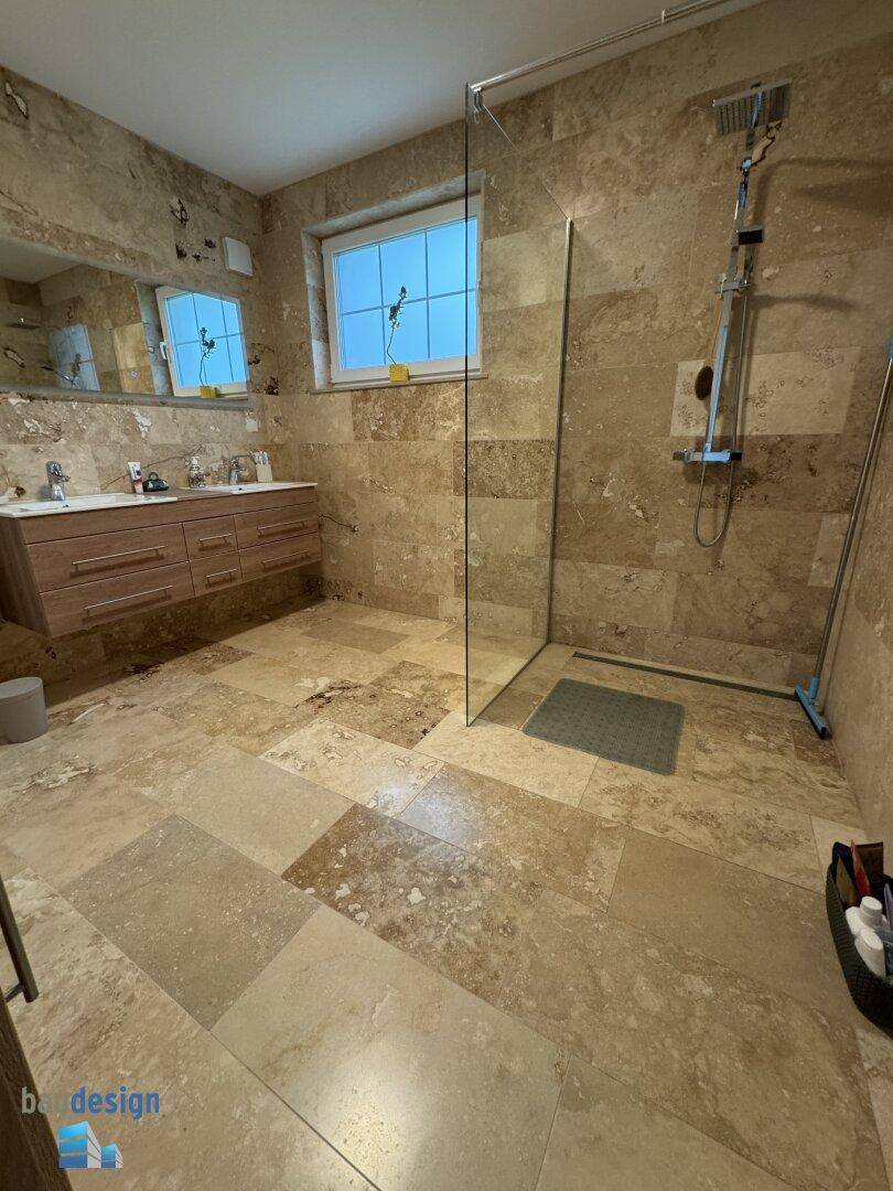 Modernes Badezimmer mit begehbarer Dusche, Doppelwaschbecken und Natursteinfliesen an Wänden und Boden.