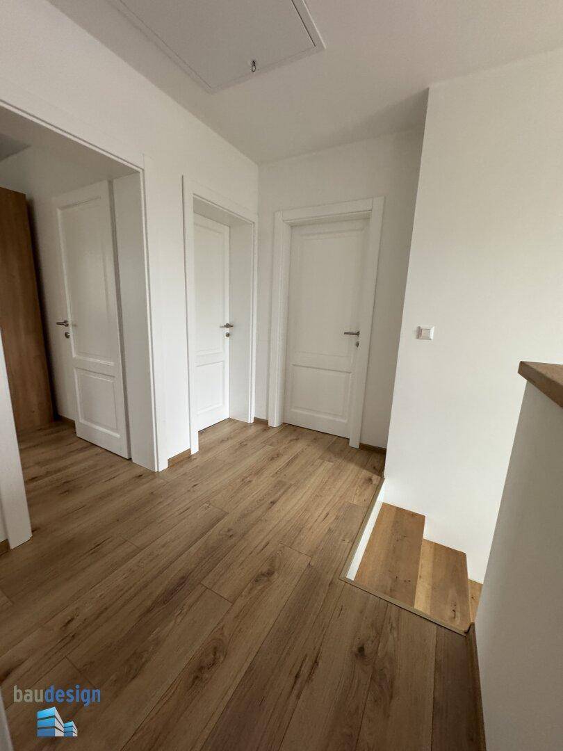 Obergeschossflur mit warmem Holzfußboden und mehreren weißen Zimmertüren.