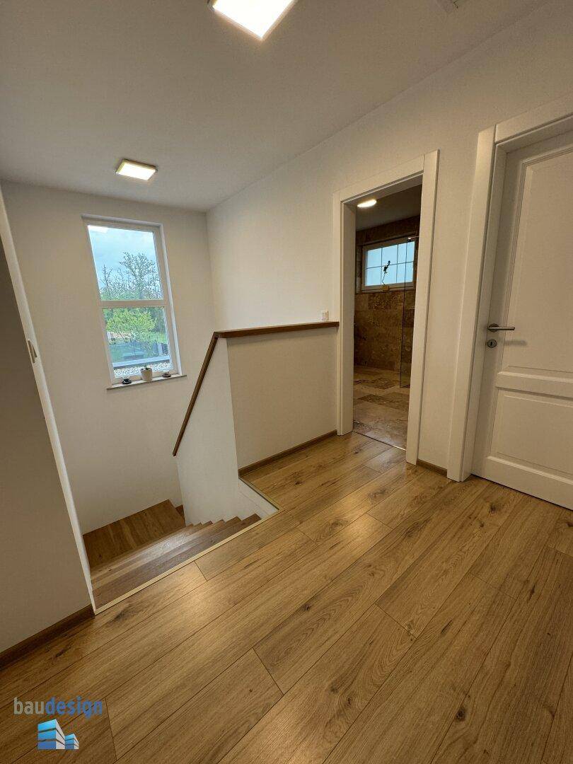 Heller Flur im Obergeschoss mit Holzfußboden und Blick auf die Treppe.