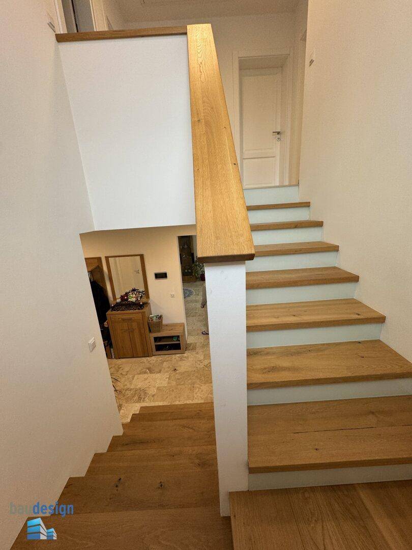 Elegante Holztreppe führt vom Eingangsbereich in die oberen Stockwerke des Hauses.