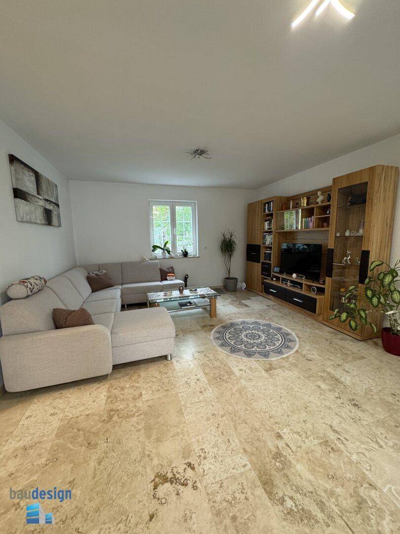 Helles Wohnzimmer mit bequemer Sitzecke, Medienschrank und dekorativem Teppich.