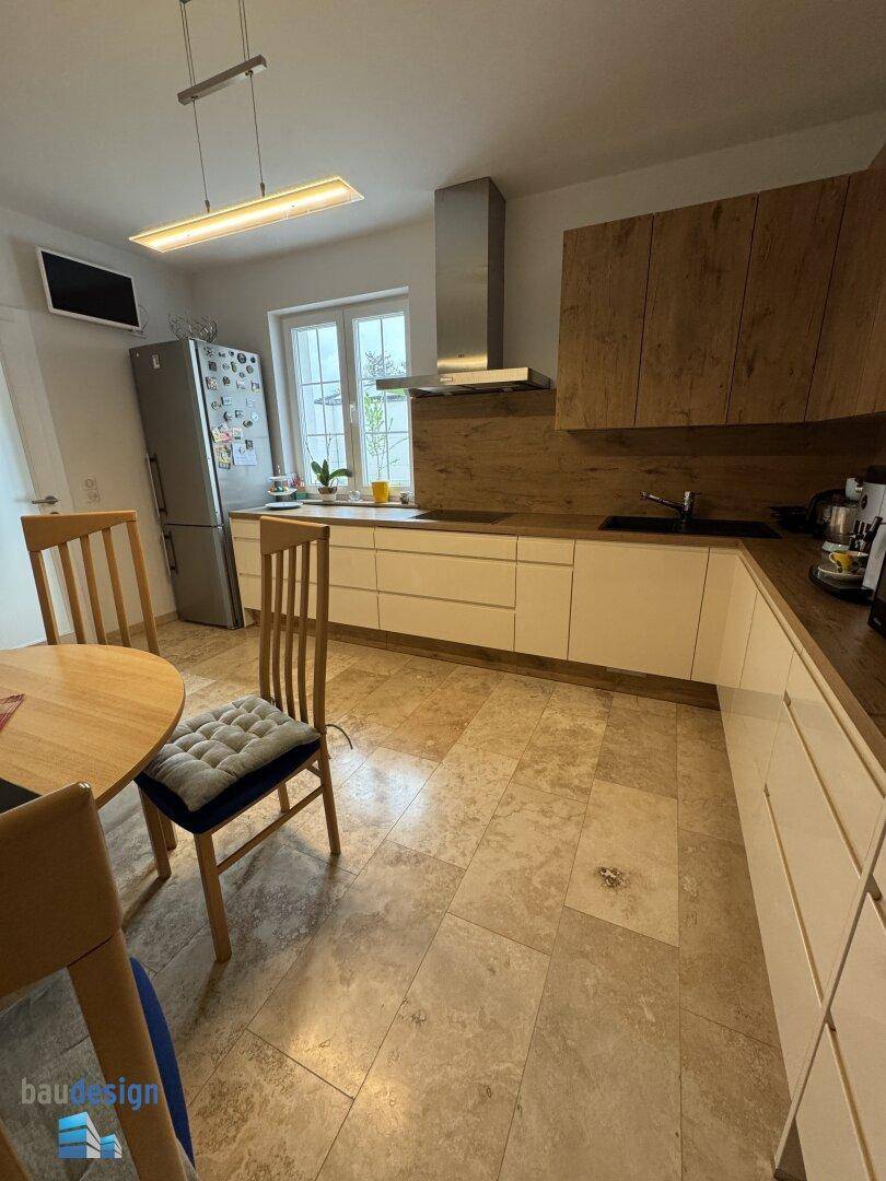 Geräumige Küche mit Essbereich, modernen Holzschränken und integrierten Geräten.