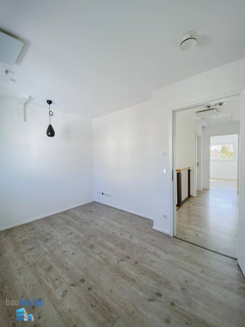 Helles Schlafzimmer mit Laminatboden und Zugang zu einem weiteren Raum.