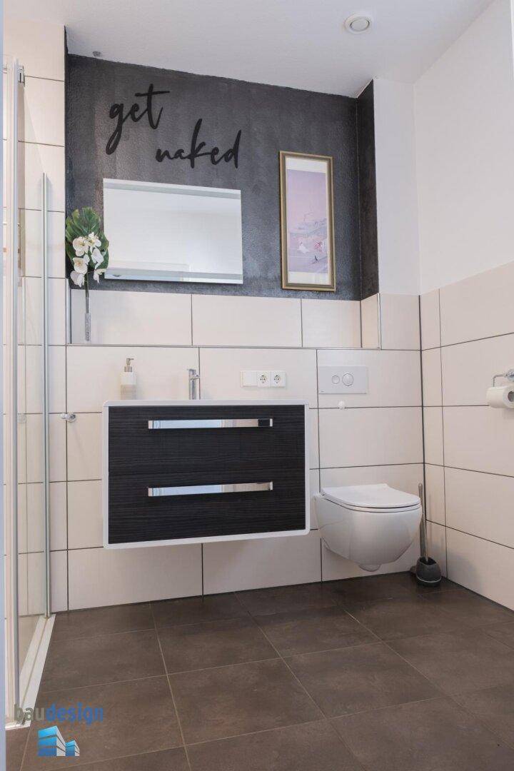 Modernes Gäste-WC mit dunkler Akzentwand, Wand-WC und Waschtisch.