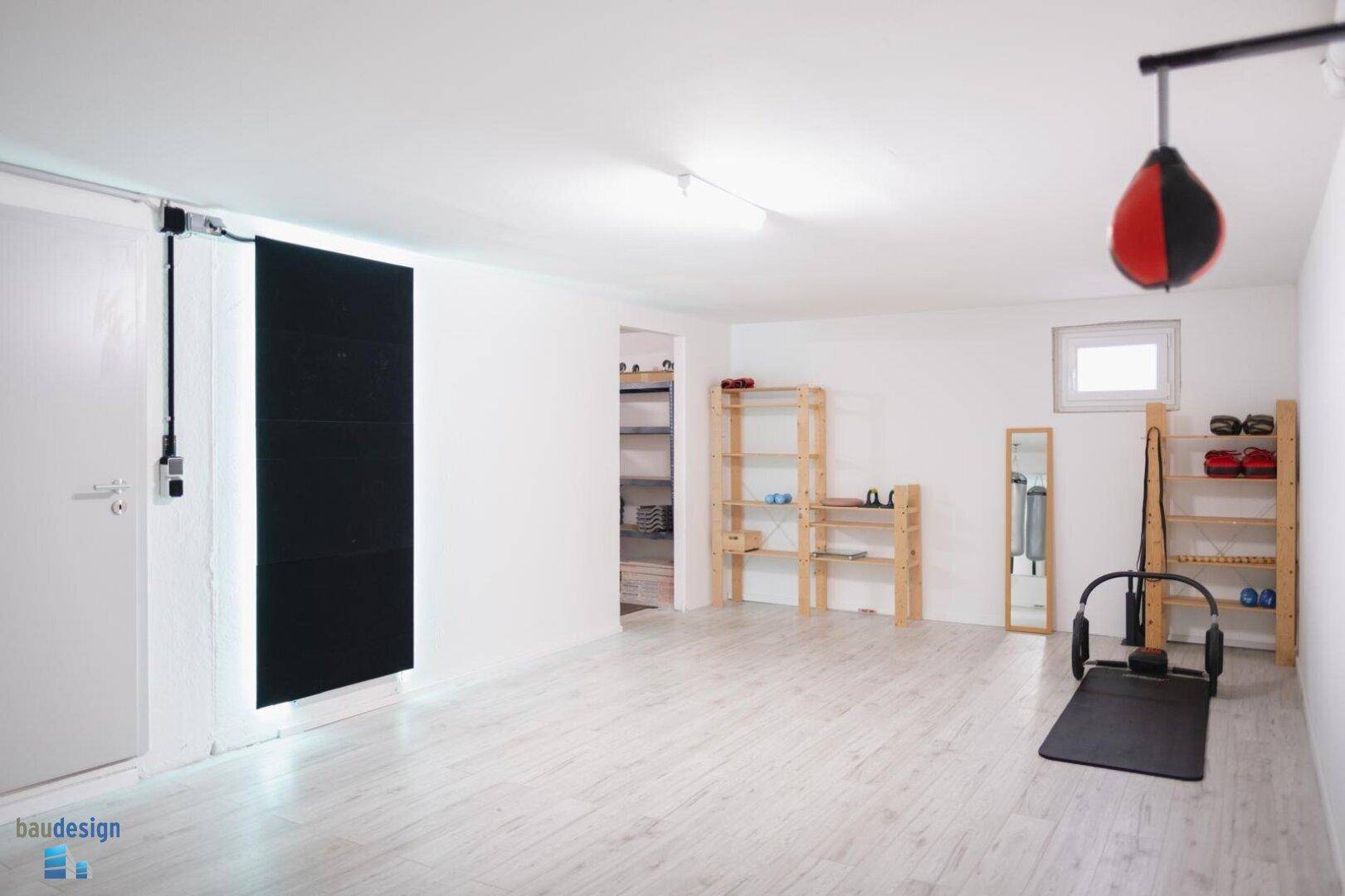 Geräumiger Hobbyraum im Keller, eingerichtet als Fitnessbereich mit Sportgeräten.