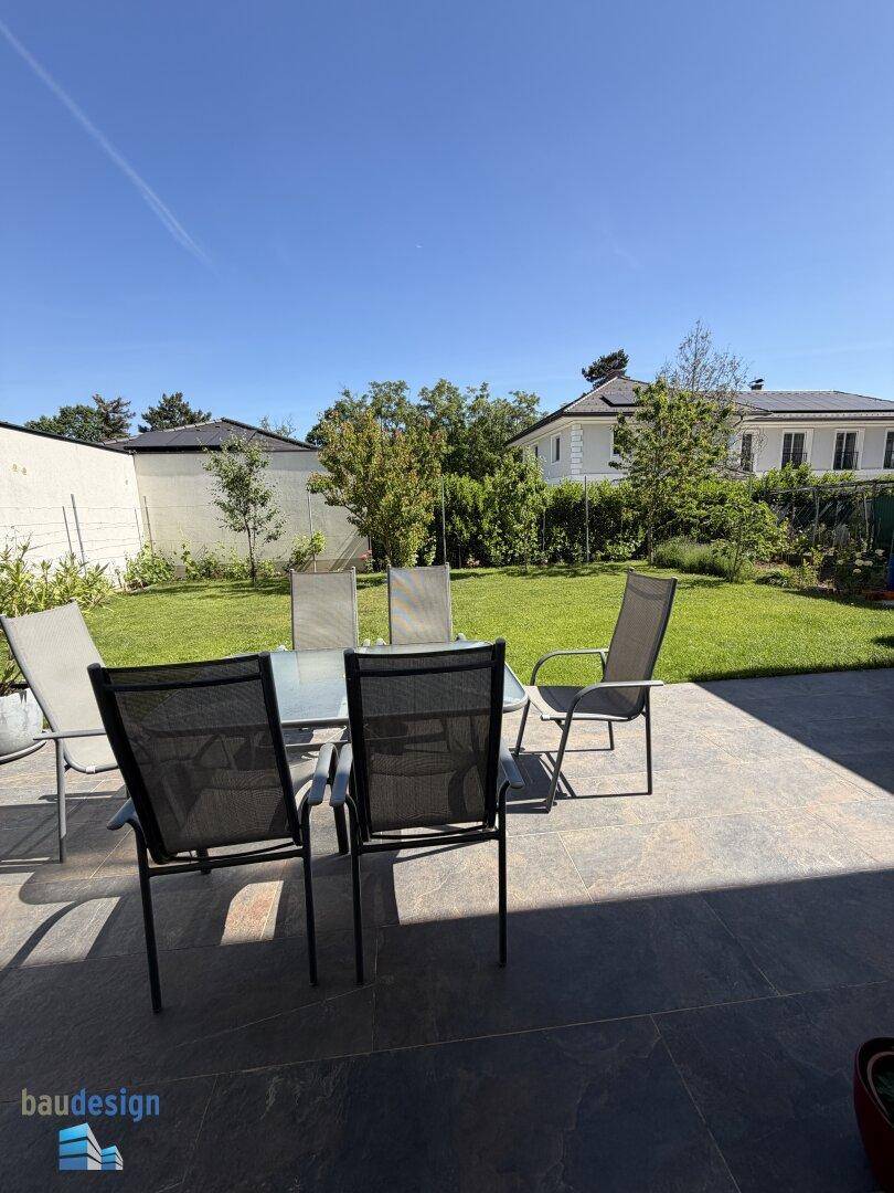 Gemütliche Terrasse mit Gartenmöbeln und weitem Blick ins Grüne an einem sonnigen Tag.