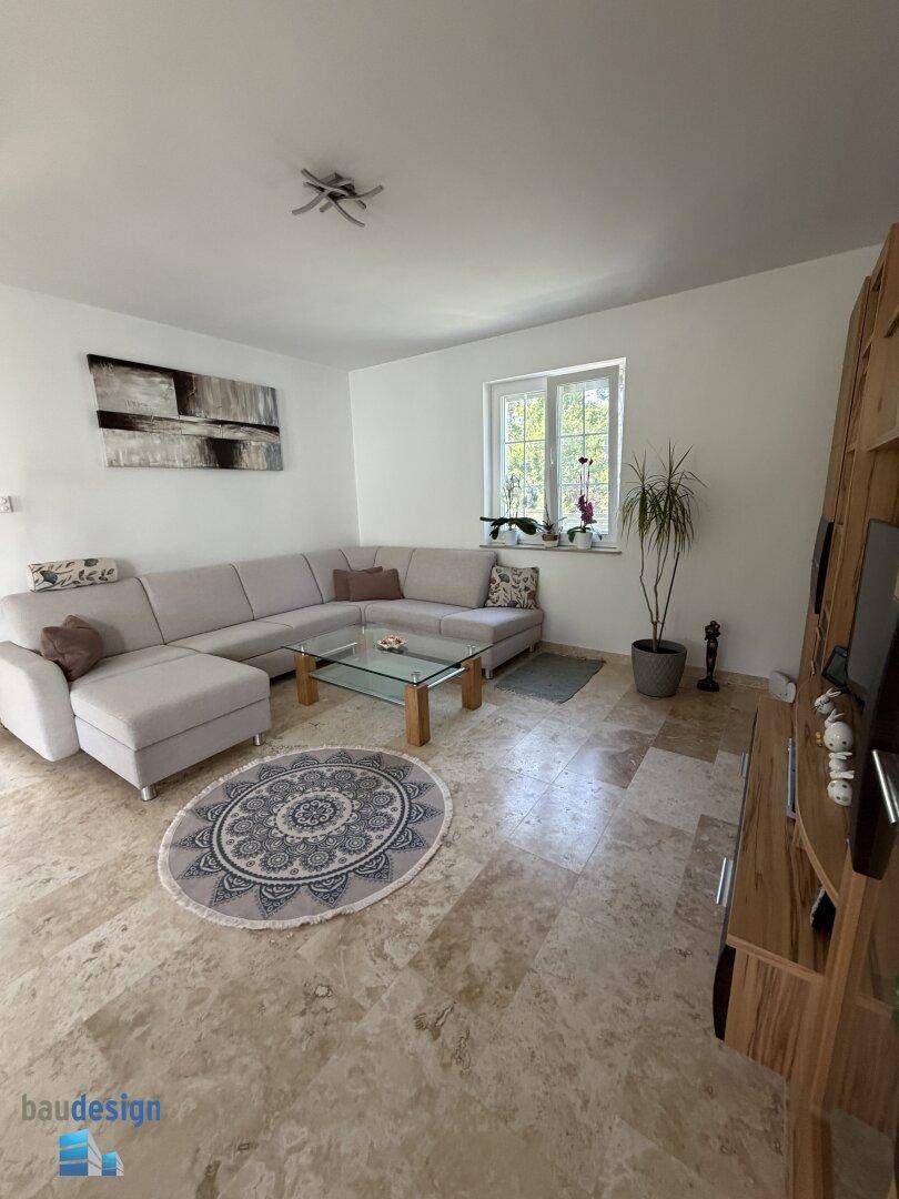 Gemütliches Wohnzimmer mit großem Ecksofa, Couchtisch und hellen Fliesenboden.